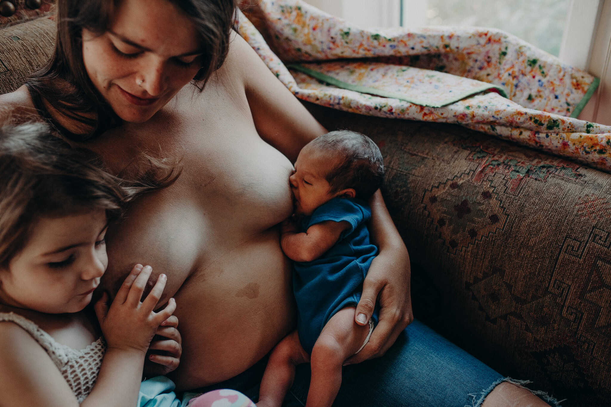 postpartum doula training bebo mia a mom tandem feeding her newborn and toddler while sitting topless on the couch